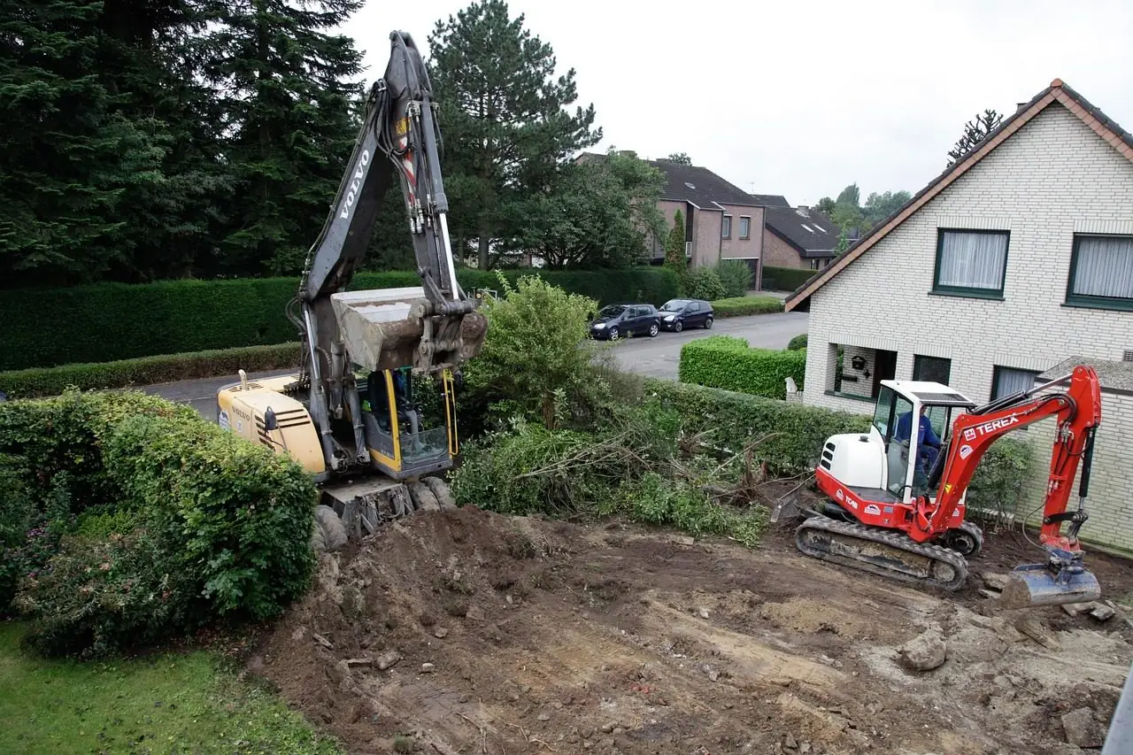 Red mini excavator digging in the garden of a house