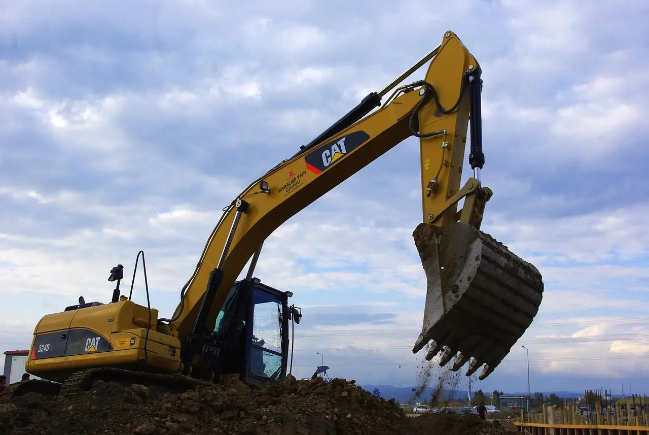 Yellow excavator with its bucket raised against a blue sky