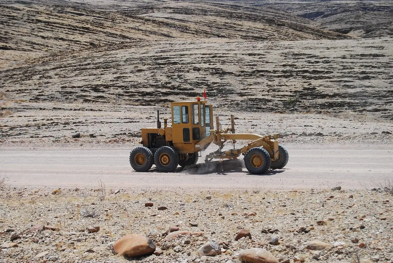 Motor grader working a wide dirt surface